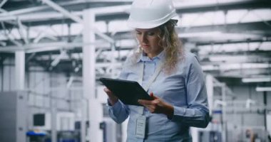 Güvenli Miğfer Giyen Odaklanmış Kadın Mühendis Yüksek Teknoloji Üretim Tesisindeki Dijital Tablet Operasyon Verilerini İnceledi. Dijital Dönüşüm kavramı, Modern Endüstriyel İş Gücü.