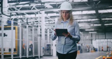 Modern Otomatik Fabrika 'da Yürürken Tablet' te Profesyonel Kadın Mühendis Yapım Verilerini Kontrol Ediyor. Akıllı Üretim Konsepti, Endüstri 4.0, Dijital Kontrol ve Verimlilik.