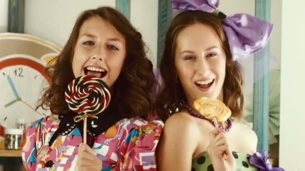 Две девушки облизывают конфеты и показывают их в камере. — стоковое видео