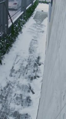 Güvenlik kamerası kayıtları, kar kaldırımından aceleyle inen, omzuna bakan adam. Adam koyu renk gözlük takıyor, siyah şapka takıyor ve Deri Torba Gergin Atmosfer ve Güvenlik Endişesi taşıyor. Dikey Çekim.