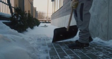 Kışlık Giysi Küreğindeki Bakım İşçisi Paved Yürüyüş Yolu 'nun Dışından Kar Küretiyor. Rutin kar temizliği sırasında eller, kürek ve botçu adam. Kış Mülkiyet Bakımı ve Güvenliği kavramı.
