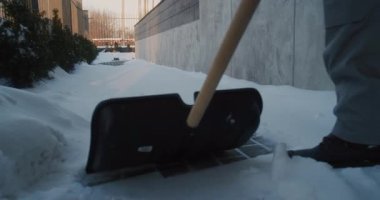 Kışlık Üniformalı İşçi Dar Kaldırımdan Temiz Kar Temizliyor Duvar Yanındaki Kürek Bina. Rutin Kar Temizleme, Mülk Bakımı, Soğuk Hava İşçi Partisi ve Kış Güvenliği Konsepti.