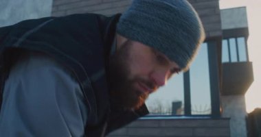 Güçlü Sakallı İşçi Konut Arazisinde Yoğun Kar Temizleme Görevi Yapıyor. Odaklanmış Emek Elle Mülk Bakımı İçin Kürek Kullanıyor. Fiziksel Dayanıklılık ve Kış Ortamı kavramı.