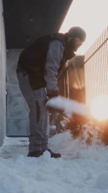 Odaklanmış Adam, Duvar ve Metal Çit 'in yanında plastik kürek kullanıyor. Düşük Sıcaklıktaki Angarya Kış İşleri sırasında Konsantrasyon ve Fiziksel Güç. Dikey Çekim.