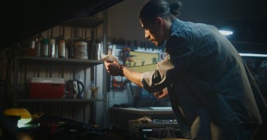 Kaldırılmış Başlıklı Altında Duran Tamirci, Dipstick 'i ve Motor Yağı Seviyesini Odaklanmış Hassasiyetle İnceledi. İnsan Kayganlaştırıcı ve Güvenilir Performans Sağlar. Koruyucu Bakım Uygulaması.