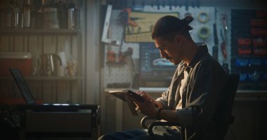 Atölyede oturan Erkek Otomotiv Uzmanı, Araç Teftişi sırasında Bilgisayarla Çapraz Referans Motoru Verisi Kullanılıyor. Akıllı Tanısal Çözümler Konsepti.