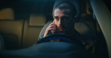 Guy, Smartphone 'da hoş olmayan telefon konuşmalarına devam ederken arabaya biniyor. Direksiyon başında oturmuş, hayal kırıklığıyla konuşuyor. İş stresi, Duygusal Gerilim ve İletişim Zorluğu.