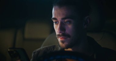 Genç adam arabada oturuyor ve Smartphone 'da sesli mesaj kaydediyor, Açık ve düşünceli konuşuyor. Modern Mobil İletişim, Kişisel Bağlantı ve Şehir Yaşam Biçiminde Dijital Etkileşim.