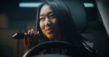 Direksiyondaki Kadın Oturuyor ve Smartphone 'daki Ses Mesajı' nı kaydediyor. Rahat ve Odaklanmış, Kız Doğal Konuşuyor, Telefonu Yakından Tutuyor. Günlük Anlık, Modern Mobil İletişim, Günlük Yaşam.