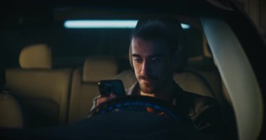 Sürücü koltuğunda oturan, Erkek Çöreğiyle Ciddi Erkek ve Bıyıklı Smartphone tutuyor, Detaylı Mesaj Yazıyor. İnsan Konsantre, Çözüm ve Amaç. Modern Mobil Etkileşimin Özel Anı.