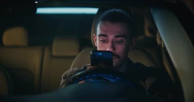 Uzun saçlı adam arabada oturur, akıllı telefondan mesajları özenle okurdu. Adam, Yanıt Yazmadan önce Düşünceli Duraklatır, Önemli, Anlamlı Konuşmaya Girer. Sosyal İletişim.