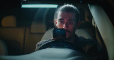 Park halindeki aracın içinde, konsantre erkek sürücü çalışmaları telefon ekranı, yavaş yavaş ciddi ciddi ciddi ciddi karşılıklı yazışmalar. İnsan Dijital Mesajla Açılan Kişisel ya da Profesyonel Tartışmaya Odaklandı.