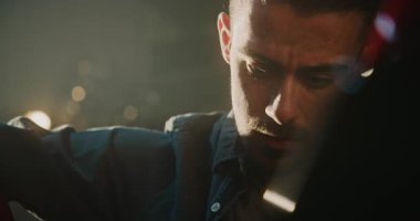 Garajda, erkek tamirci kasıtlı olarak tornavidayla batarya montaj cıvatalarını söker. Mans Sabit Hareketler ve Yoğunlaştırılmış İfade Pratik Uzmanlık ve Motosiklet Tamiri Adanmışlığı.