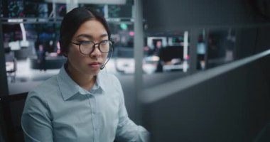 Genç Asyalı Kıtır Mavi Gömlek Uzmanı, Gerçek Zamanlı Analitik Kontrol Panellerine odaklanmış. Anında İletişim için profesyonel kulaklık takan bir kadın. Yatırım Ortamı Yeni Nesil Uzmanları.