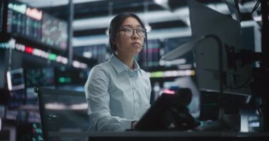 Gerçek Zamandaki Borsa Verilerini Büyük Ekranlarda Analiz Eden Kadın Tüccar. Gözlüklü Odaklanmış Asyalı Kadın Yüksek Teknoloji Masasında İsteyerek Çalışıyor, Kompleks Mali Tabloları İzlerken Klavyede Yazıyor.