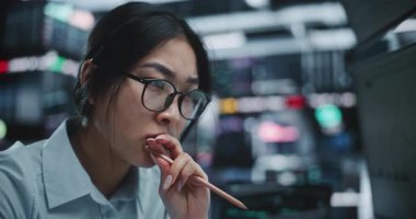 Yüksek Odaklı Asyalı Kadın Tüccar Elinde Kalem Verisiyle Geniş Pazar Verilerini Analiz Ediyor. Kız Düşünerek Parmaklar Arasında Kalem Döndürüyor. Yüksek Teknolojik Dijital Borsa Stratejik Analizi.