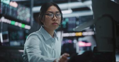 Piyasa Değişiklikleri Üzerine Meslektaşları azarlamak için Asyalı Kadın Denetleyici Şirket Telefonunu kullanıyor. Ciddi Kadın Ekranlarda Değişen Analizleri İzliyor ve Masa Başındaki Telefona Katı Talimatlar Veriyor.