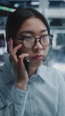 Bilgisayar 'da Borsa Operasyonları Çalıştırılırken Akıllı Telefon' da Asyalı Kadın Konuşmaları. Canlı Çizelgeler ve Fiyat Hareketleri, Mevcut Piyasa Eğilimleri Kadın Raporları, Dalgalanmalar. Dikey Çekim.