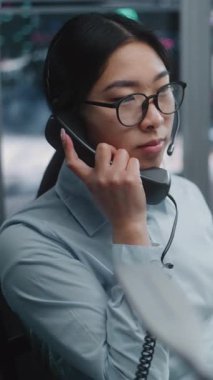 Modern Ticaret Merkezi 'nde Canlı Finansal Verileri İzlerken Asya Borsası Operatörü sabit hat telefonundan konuşuyor. Kadın, müşterilerle piyasa işlemlerini ve iletişimini yönetiyor. Dikey Çekim.