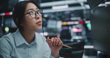 Enerjik Asyalı Kadın Dijital Ofiste Müşteri Kulaklığı ile Tartışıyor. Kadın, Ekrandaki Gerçek Zaman Verilerini Aktif İzlerken Kritik Borsa Anlaşması Hakkında Müşteriyle İletişim Kuruyor.