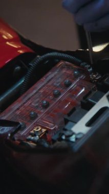 Koruyucu Eldiven Giyen Kadın Motorsikletin Batarya Terminallerinde Sürgüleri Gevşetmek için Tornavida Kullanıyor. Elektrik Servisi Hassasiyeti ve Garaj Ayarlarındaki Bisiklet Tamirine Yaklaş. Dikey Çekim.