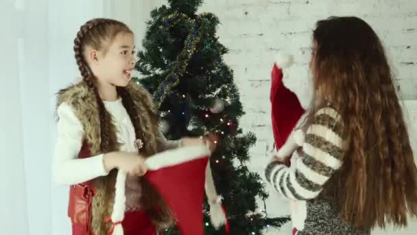 Duas meninas usam chapéus de Papai Noel uma para a outra — Vídeo de Stock