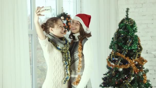 Zwei Teenager-Freundinnen machen Selfie auf dem Hintergrund Weihnachtsbaum — Stockvideo