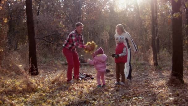 Семья веселится в осеннем парке и выбрасывает листья — стоковое видео