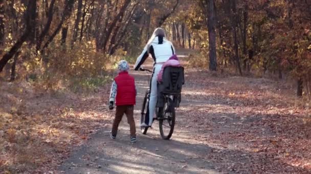 Mutter fährt mit Kindern Fahrrad im Herbstpark — Stockvideo