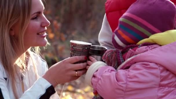 Mother gives some tea to children in autumn park — Stock Video