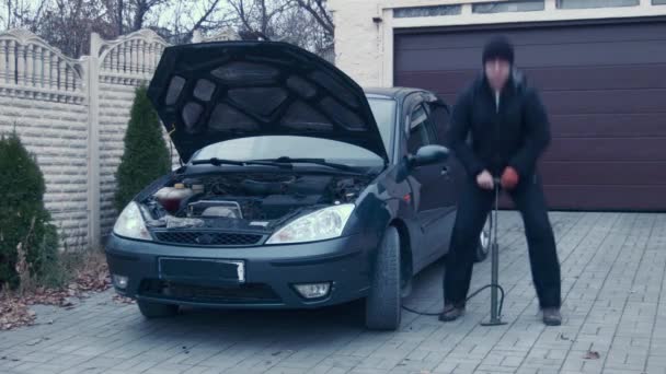 O homem ridiculamente infla rodas do carro — Vídeo de Stock