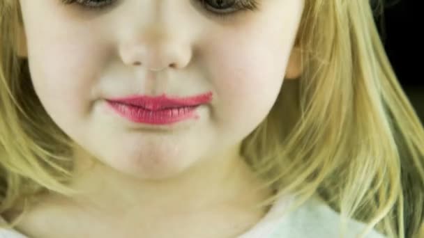 The little cute girl makes up lips with red lipstick — Stock Video