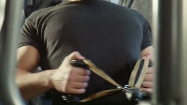 Adam bir spor salonu egzersiz makinesi üzerinde çalışmaktadır