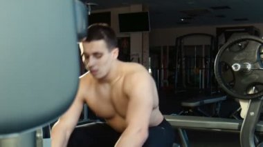 Adam bir spor salonu egzersiz makinesi üzerinde çalışmaktadır