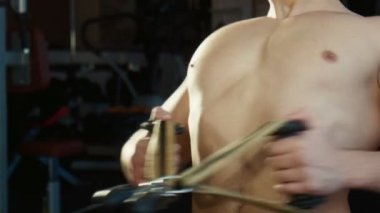 Adam bir spor salonu egzersiz makinesi üzerinde çalışmaktadır