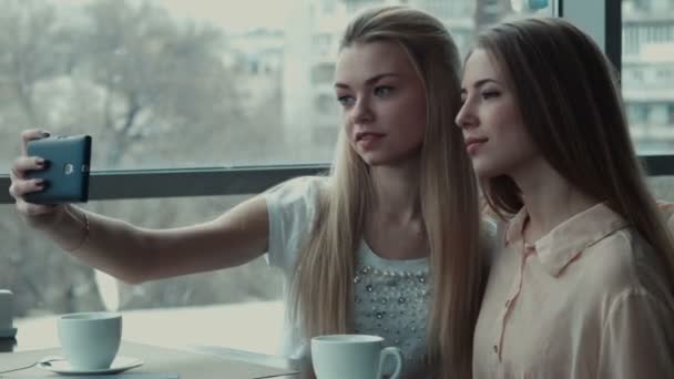 Две девушки делают селфи в кафе — стоковое видео