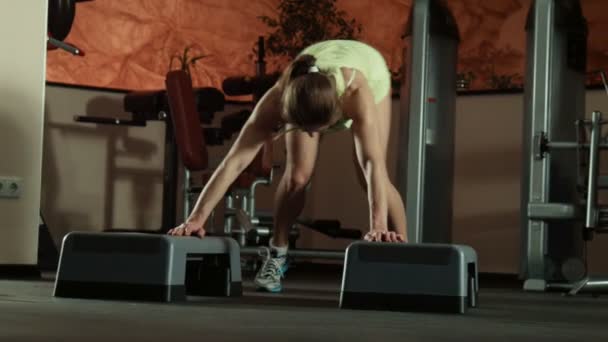 La mujer hace flexiones en los pasos de fitness — Vídeo de stock