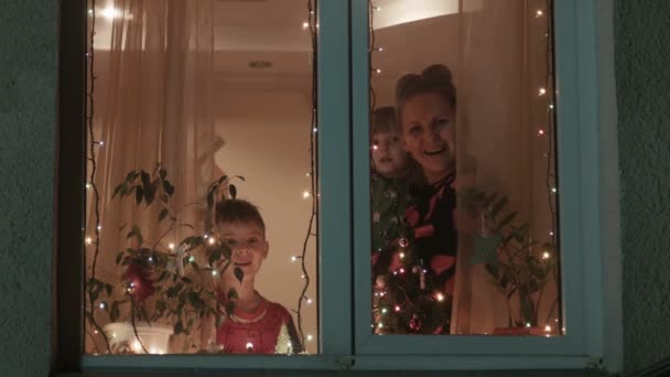 Navidad, madre e hijos corren hacia una ventana y miran al cielo — Vídeos de Stock