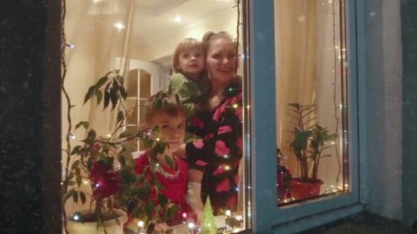 Weihnachten laufen Mutter und Kinder vor ein Fenster und schauen auf Schnee — Stockvideo