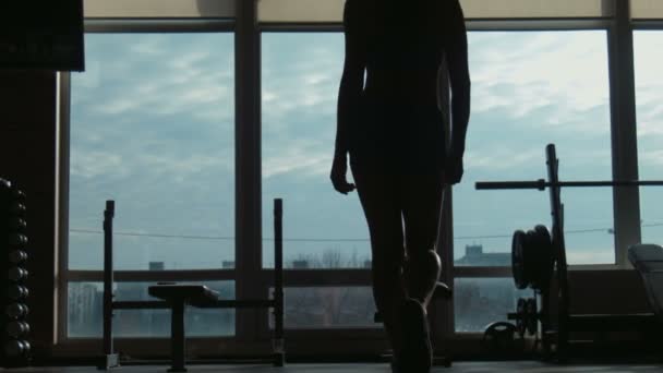 Силуэт привлекательной женщины, идущей на фитнес-студию к окну — стоковое видео