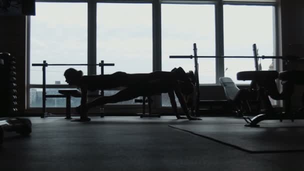 Σιλουέτα, δύο κορίτσια κάνει push-ups μαζί σε ένα γυμναστήριο — Αρχείο Βίντεο