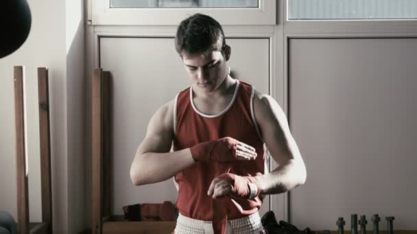 The young boxer pulls red bandage on hands and fight poses — Stock Video