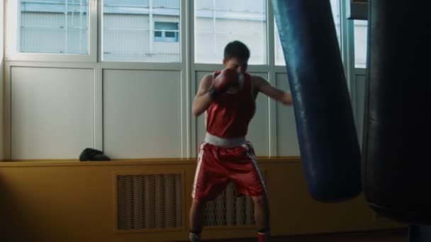 El joven boxeador entrenando en gimnasio con saco de boxeo — Vídeos de Stock