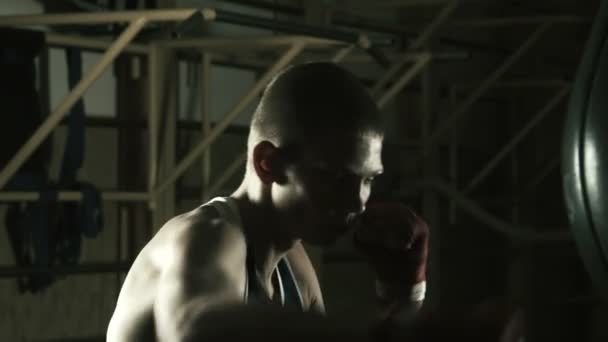 Молодой боксер тренируется в спортзале с боксерской грушей — стоковое видео