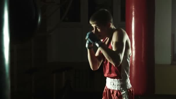Молодой боксер бьет боксерскую грушу в спортзале — стоковое видео