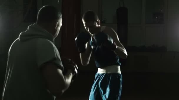 Тренер по боксу тренирует молодого боксера — стоковое видео