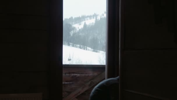 Het kind kijkt naar de sneeuw door een raam — Stockvideo