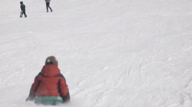 Bir tepe üzerinde bir kızak üzerinde çocuk tırmanıyor