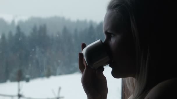 Mujer tiene té cerca de una ventana en invierno en el complejo — Vídeo de stock