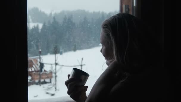 Female has tea near a window in winter in resort — Stock Video